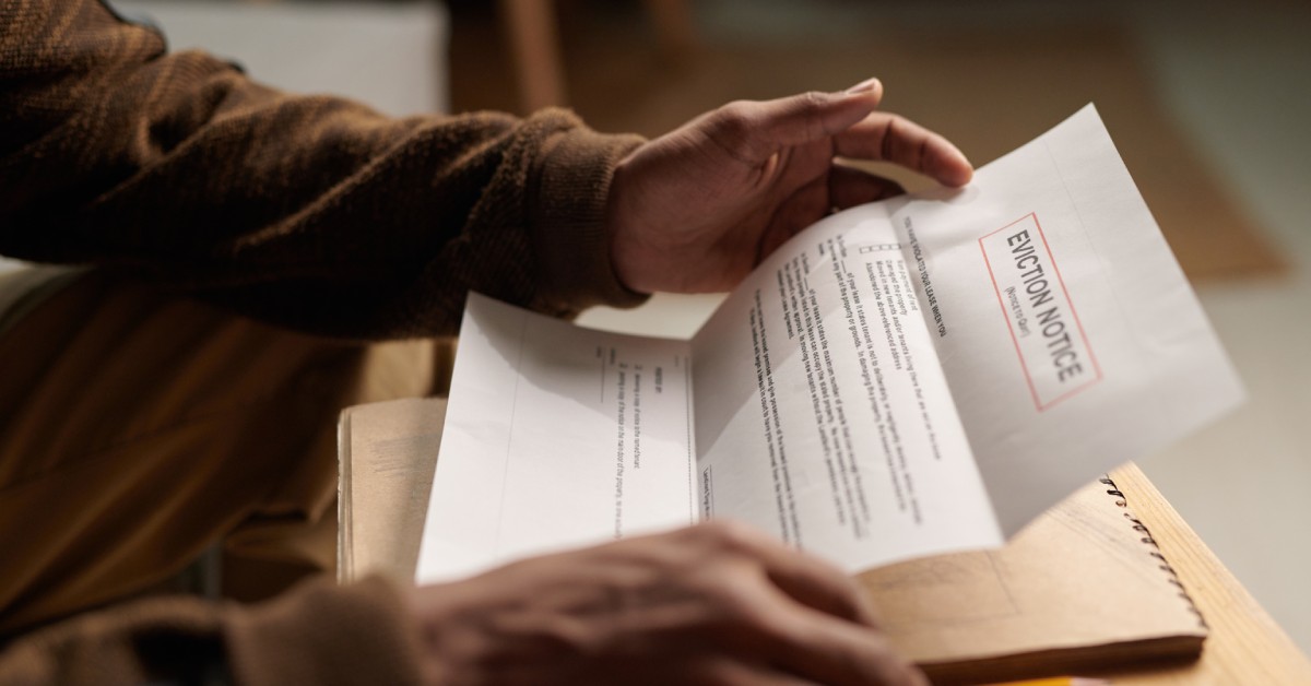 A close-up of a person's hands holding a sheet of paper that reads "EVICTION NOTICE" at the top with more text below.