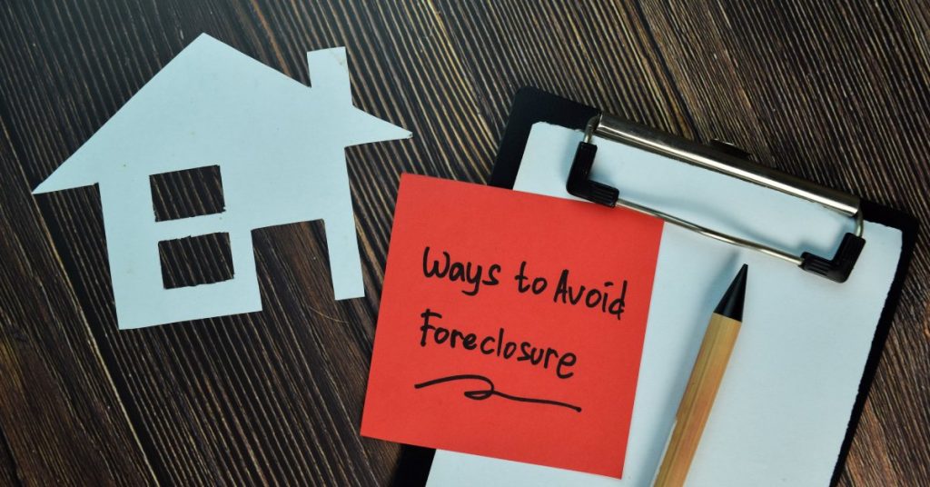 A red sticky note reads, "ways to avoid foreclosure." The note is on a clipboard with a silhouette of a house to the left.