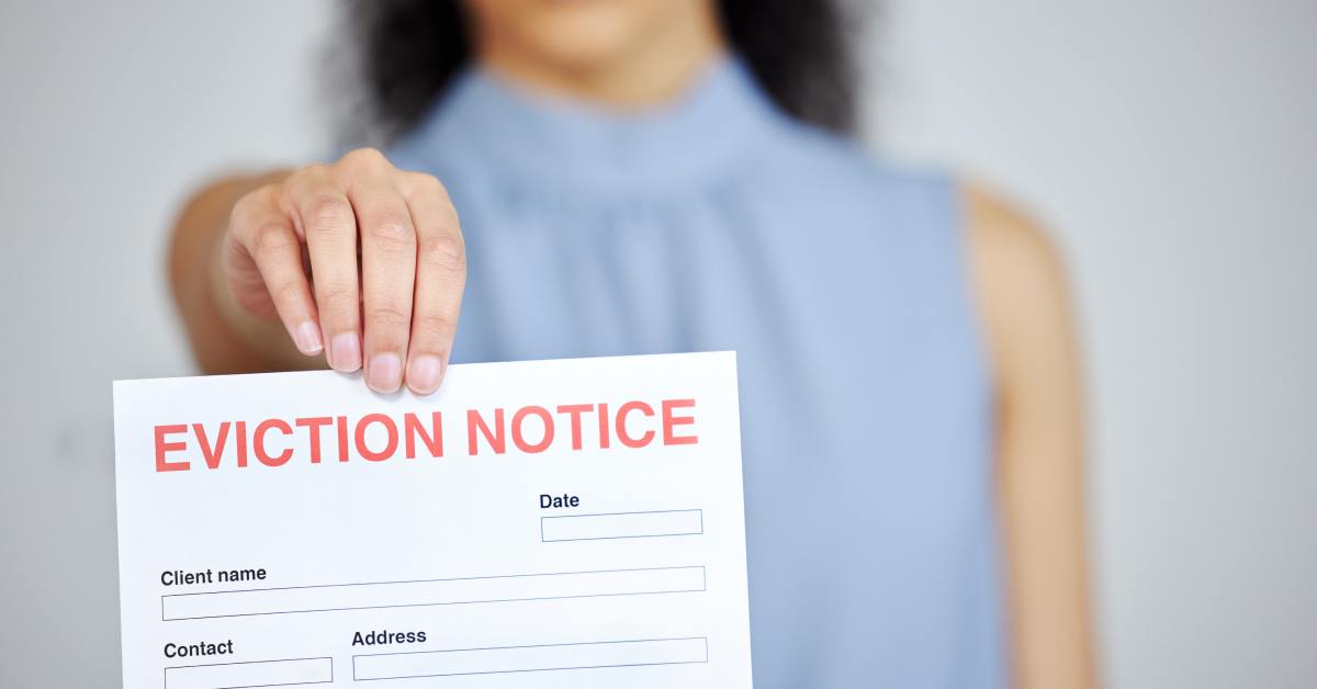 A woman in a blue sleeveless blouse is blurred while holding a white eviction notice document toward the viewer.